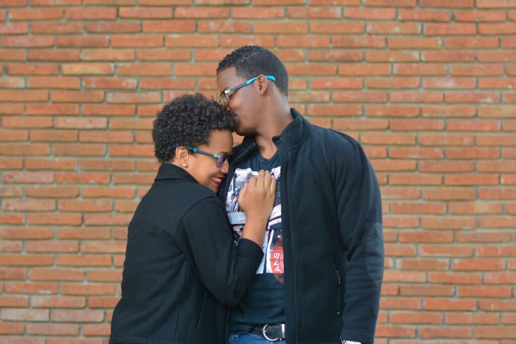 A couple dancing and hugging in front of a brick wall