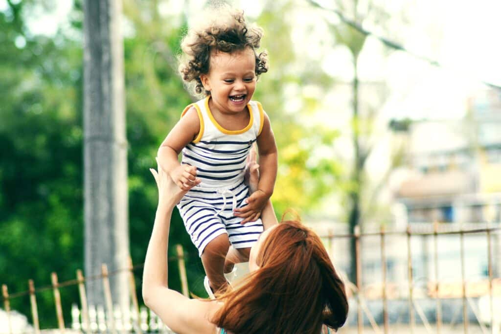 Woman outside, holding laughing child above her