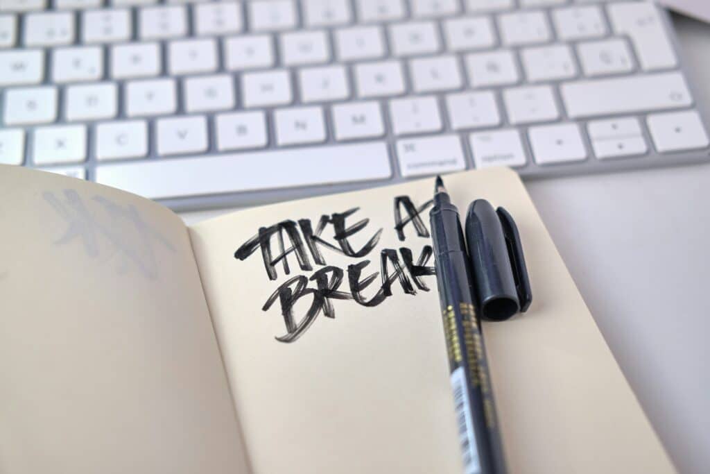 Notebook next to keyboard with take a break written in black marker.