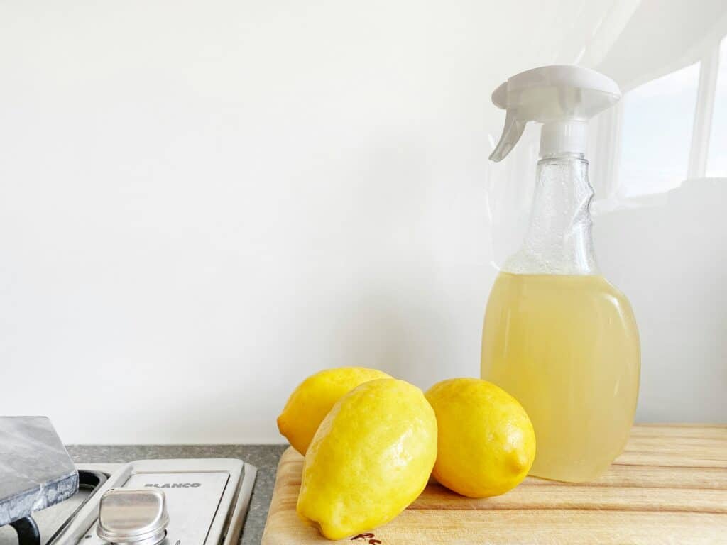Lemons on countertop beside clear spray bottle