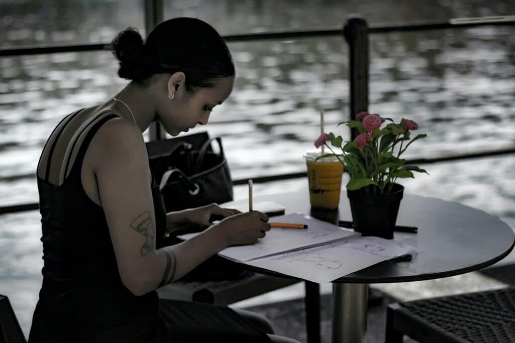 Woman journaling at a table by the water